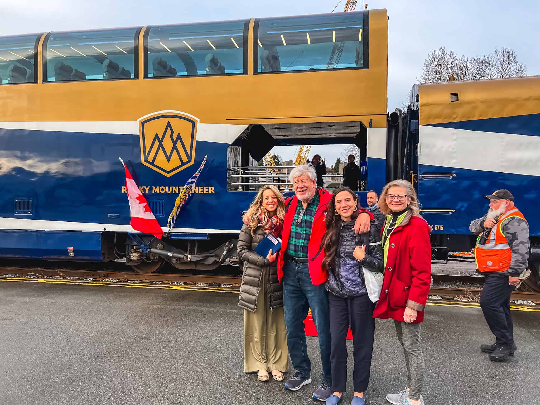 Family posing beside Rocky Mountaineer train before departure on luxury rail journey through British Columbia