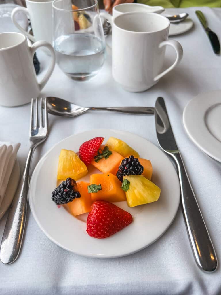 Fresh fruit plate with strawberries, cantaloupe, pineapple, and blackberries served onboard luxury train travel through Canada