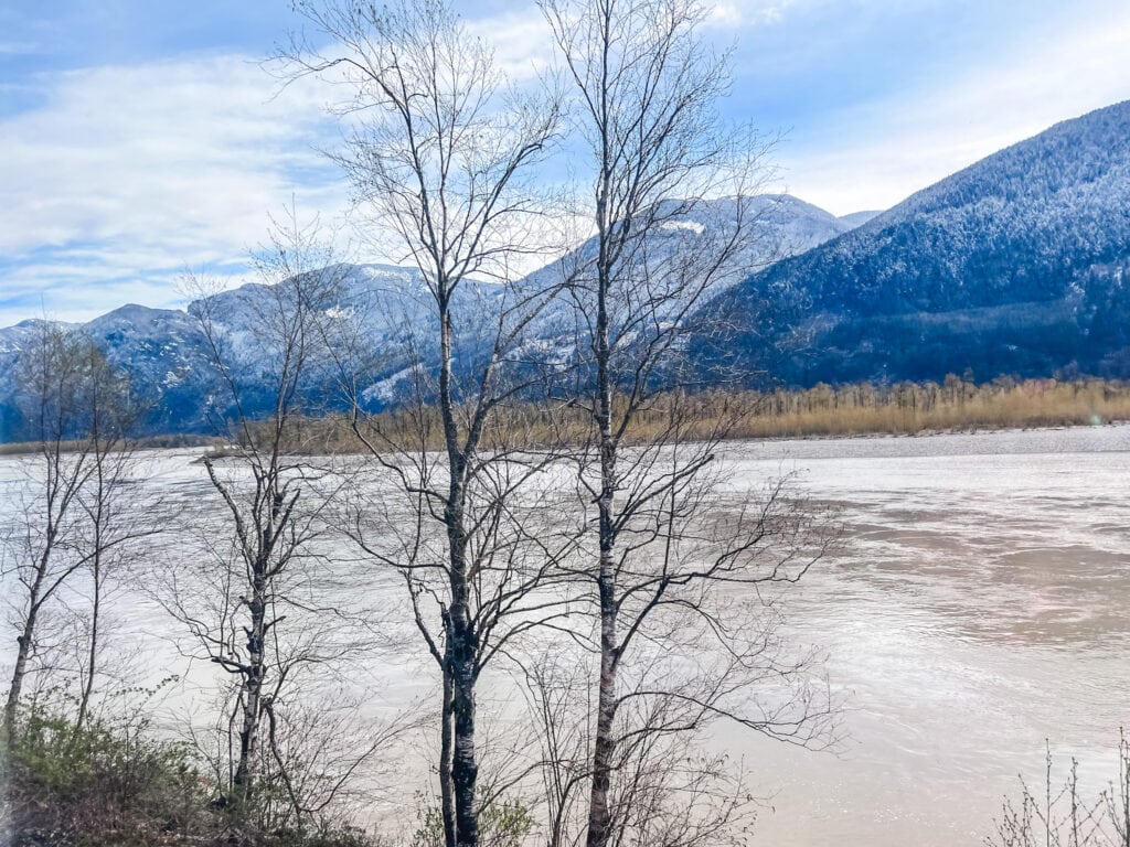 Winter landscape view of frozen lake surrounded by snow-capped mountains along Canadian railway route