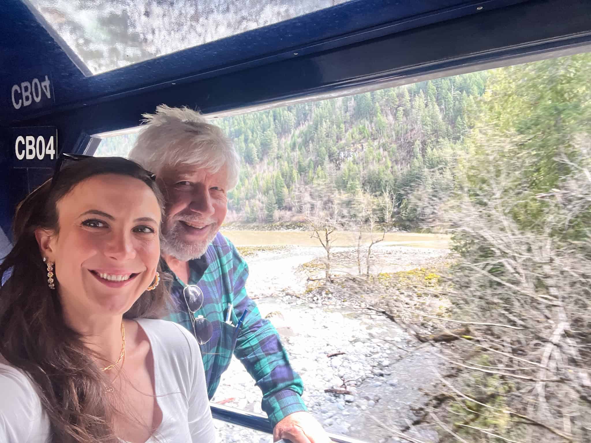 Passengers on outdoor viewing platform between GoldLeaf coaches watching Fraser Canyon scenery during scenic rail journey