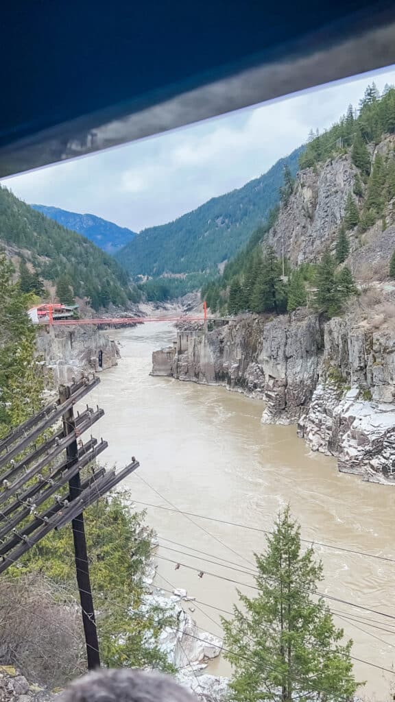 Rocky Mountaineer train passing through Fraser Canyon with dramatic river gorge and railway bridges on First Passage to the West route