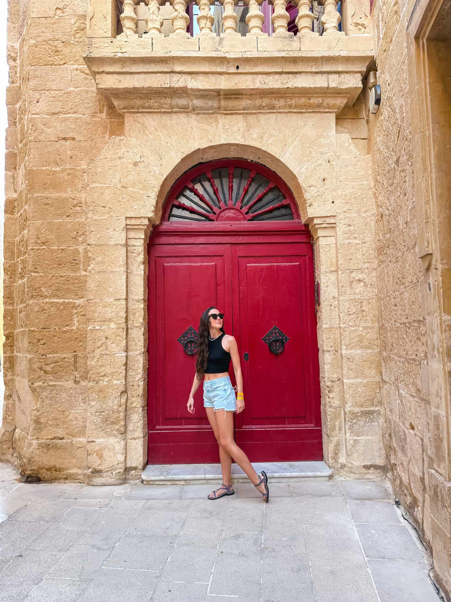 Woman posing in front of iconic red door with baroque architecture in Mdina during 3 days in Malta itinerary