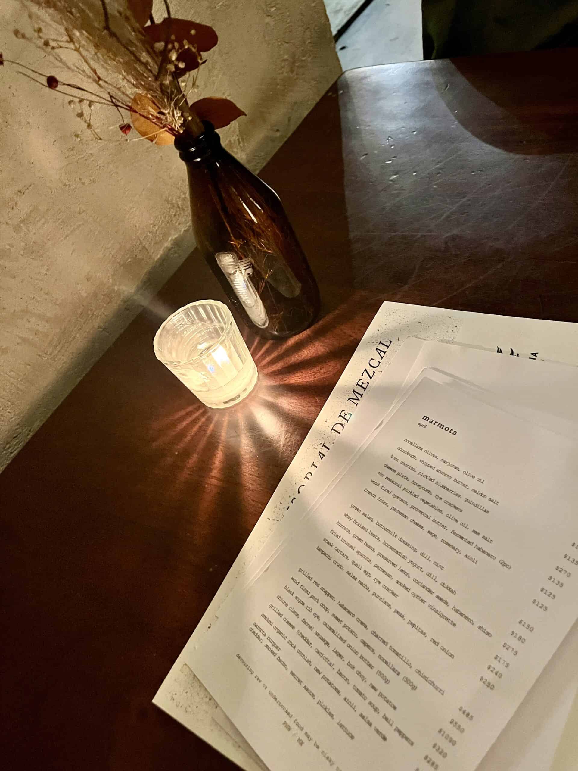 candle shining next to dinner menu at Marmota for 4 days in mexico city
