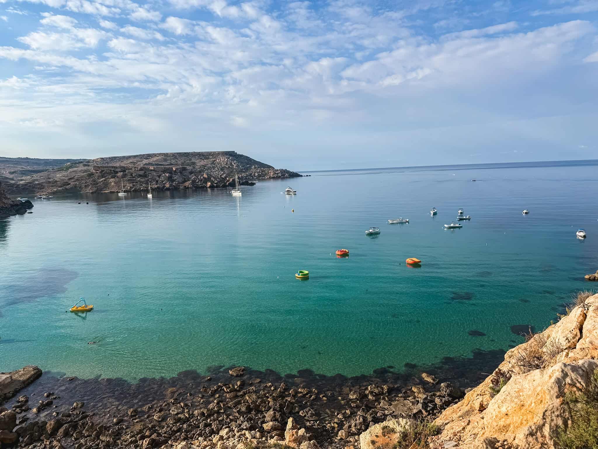 Scenic Malta bay with turquoise Mediterranean waters, colorful boats, and dramatic rocky coastline during one week in Malta