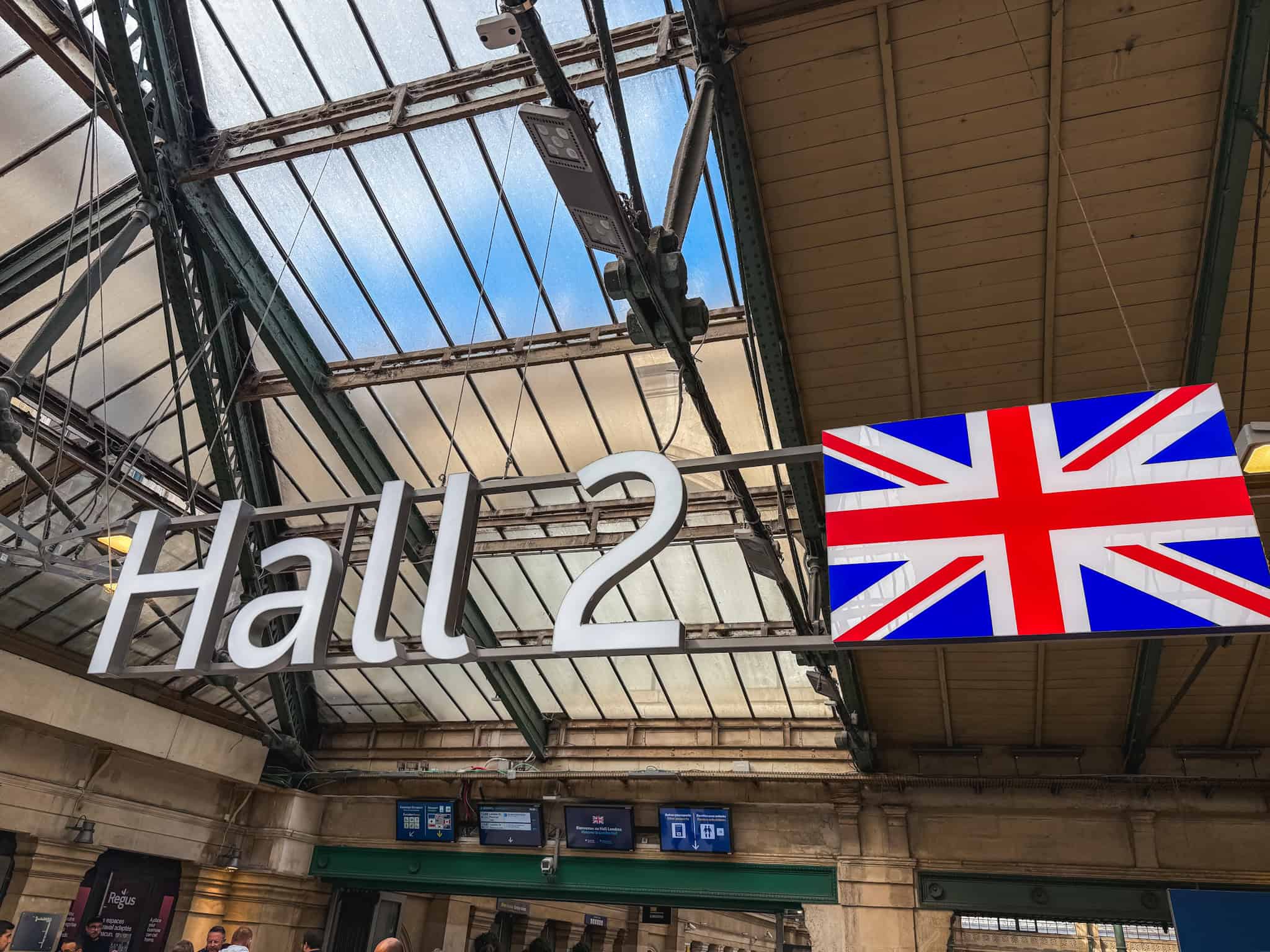 Hall 2 sign with Union Jack flag hanging from the glass and iron ceiling of the Gare du Nord Eurostar terminal in Paris