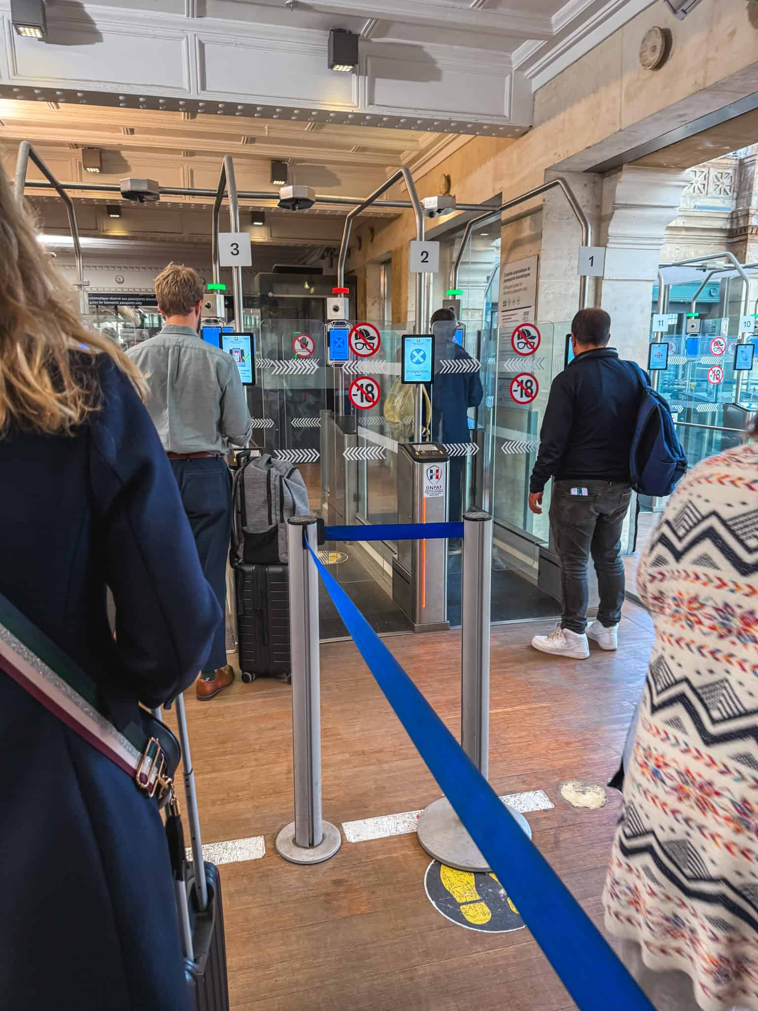 Passengers queuing at automated biometric passport control gates with face scanners inside the Eurostar terminal before boarding the train from paris to london