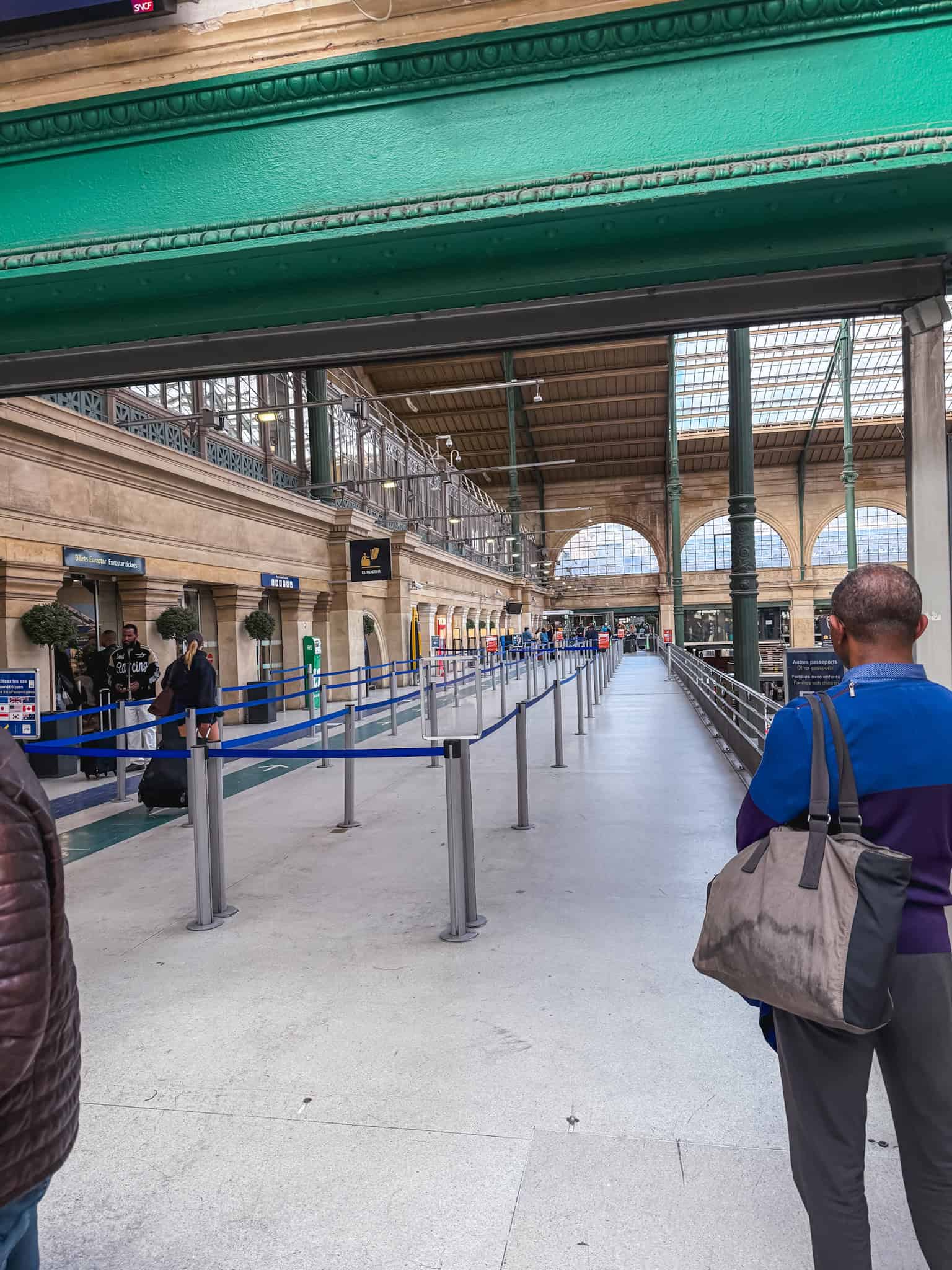 Long blue rope queue line stretching through the grand Eurostar departure hall at Gare du Nord leading toward passport check and boarding