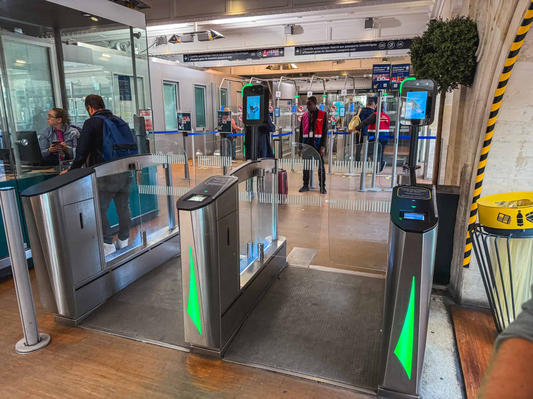 Row of automated ePassport immigration gates with green-lit turnstiles and scanning kiosks at the Gare du Nord Eurostar departure hall