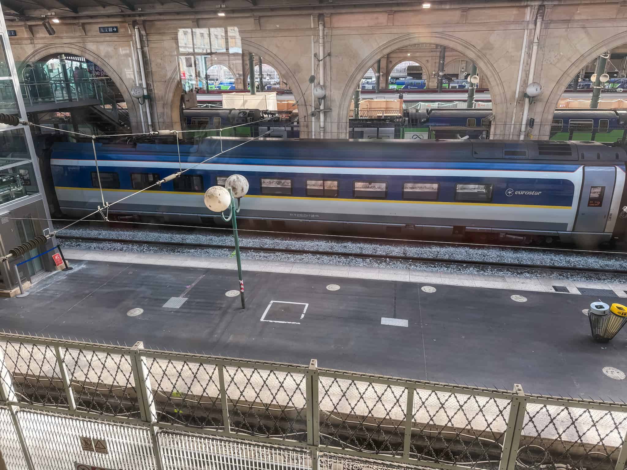 Eurostar train at the Gare du Nord platform viewed from an upper level showcasing the station's magnificent stone arches and iron roof