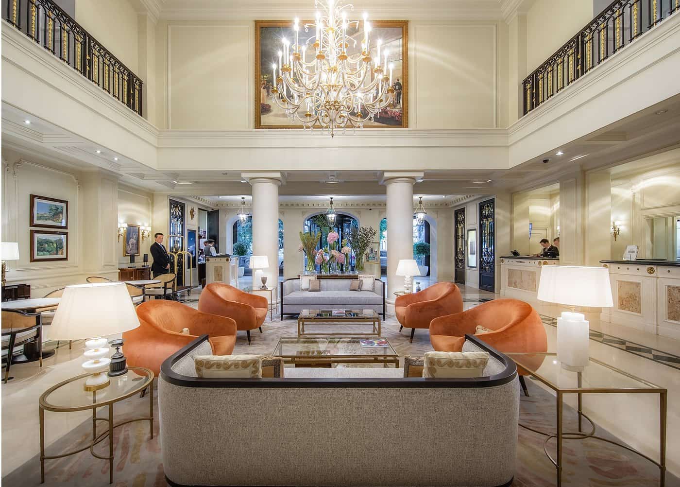 Grand luxury hotel lobby in Monaco with crystal chandelier, orange velvet armchairs, marble floors and double-height ceilings — where to stay in Monaco