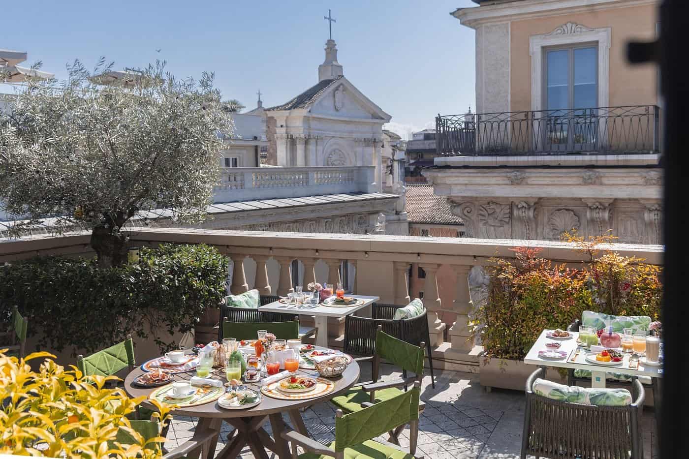 Rooftop breakfast terrace at a luxury Rome hotel with views of a Baroque church facade — European summer vacations dining experience in Italy