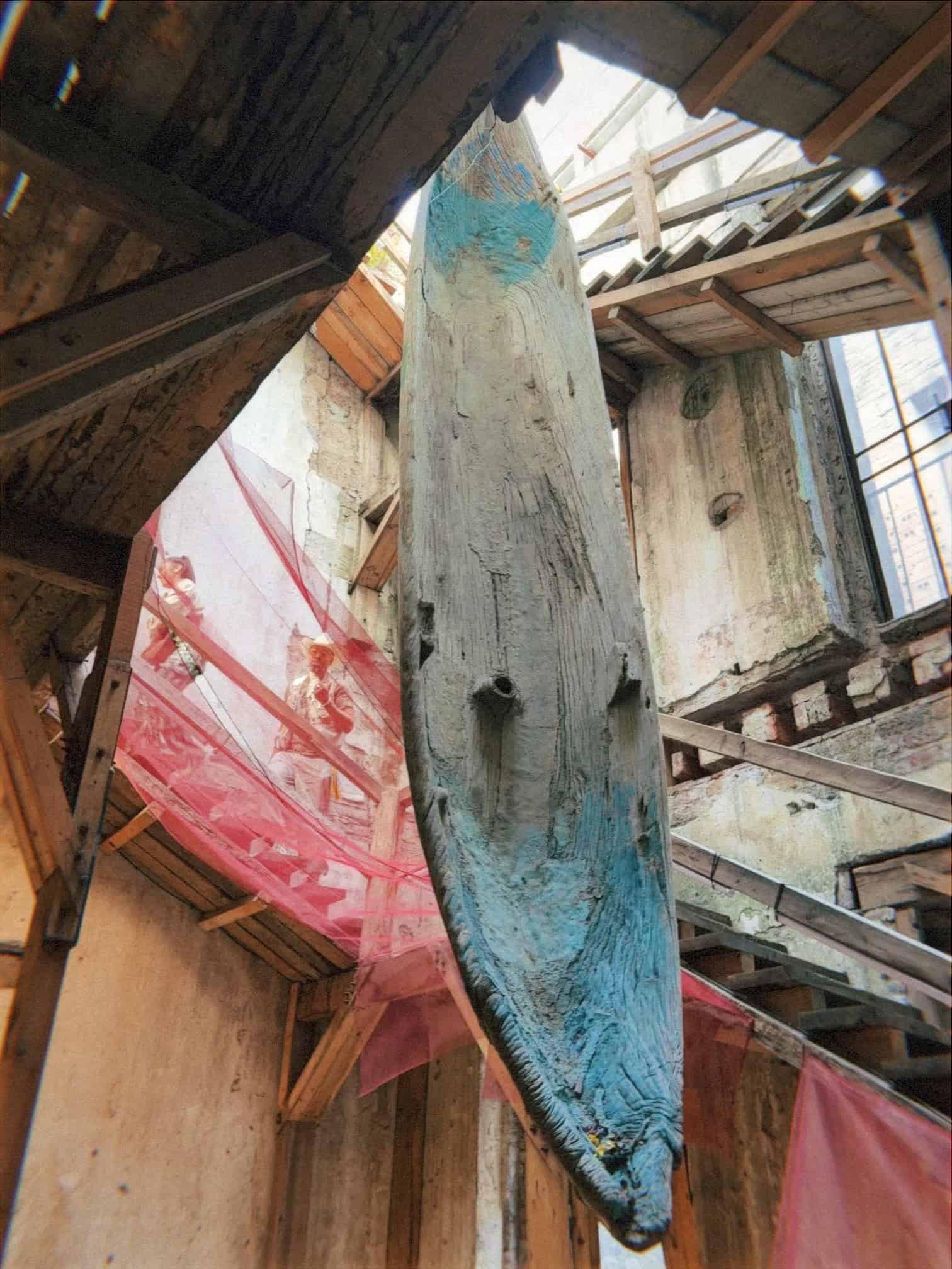 Weathered wooden canoe installation with painted fabrics at art events Mexico City gallery space