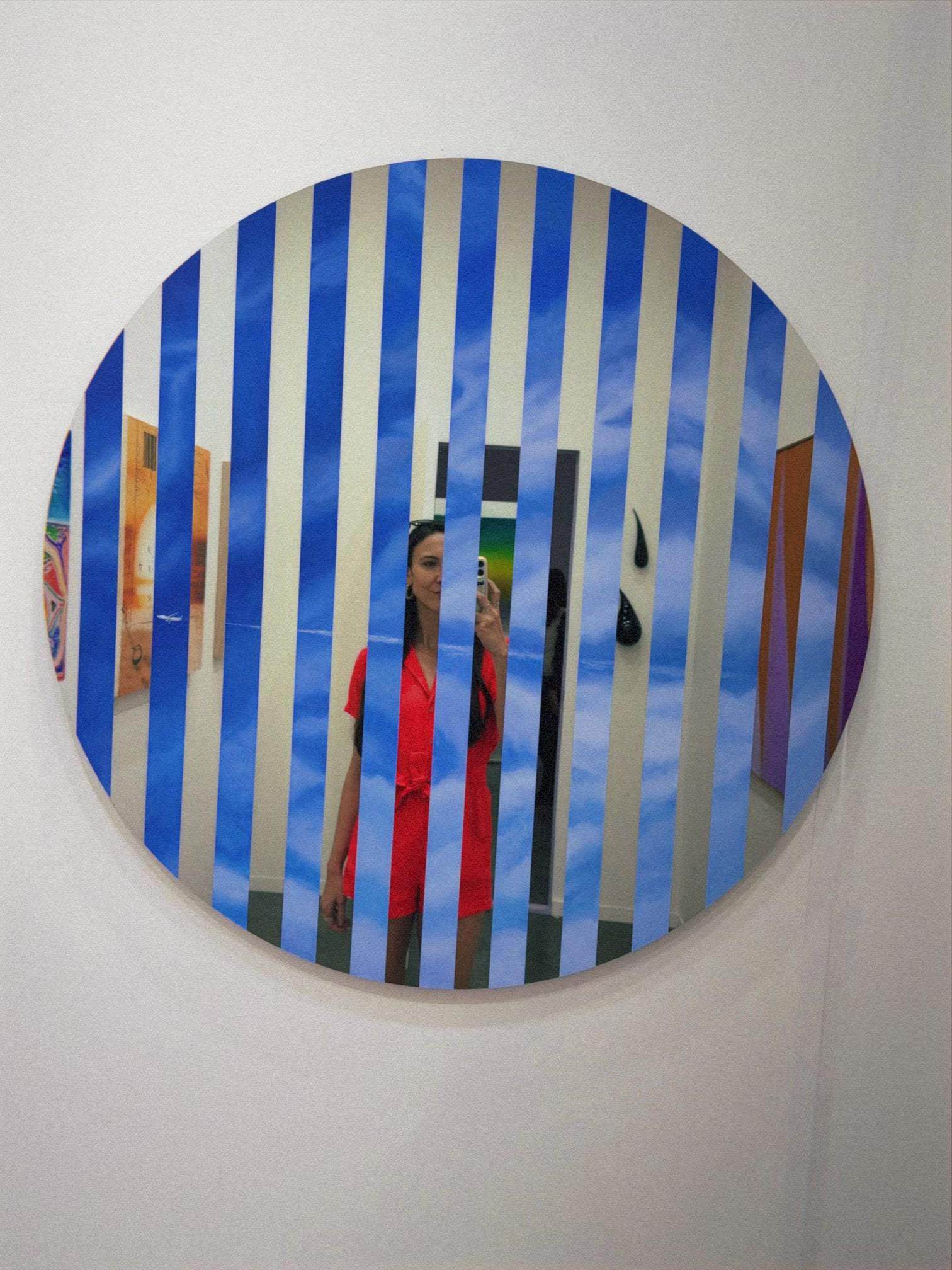 Visitor photographing circular striped mirror art installation at contemporary art Mexico City exhibition