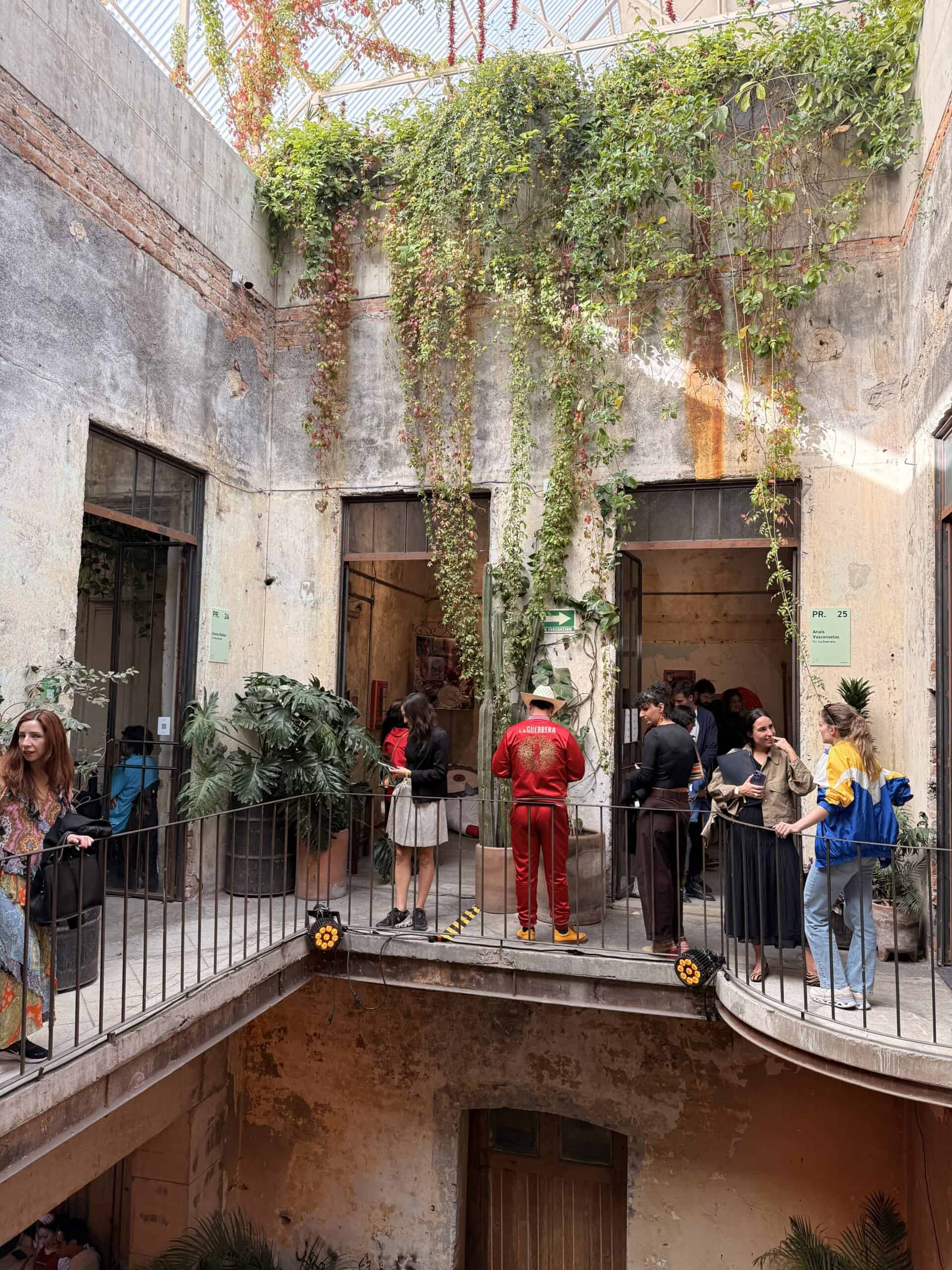 : Vine-covered courtyard balconies with visitors at Mexico City art scene gallery hop event Salon Acme
