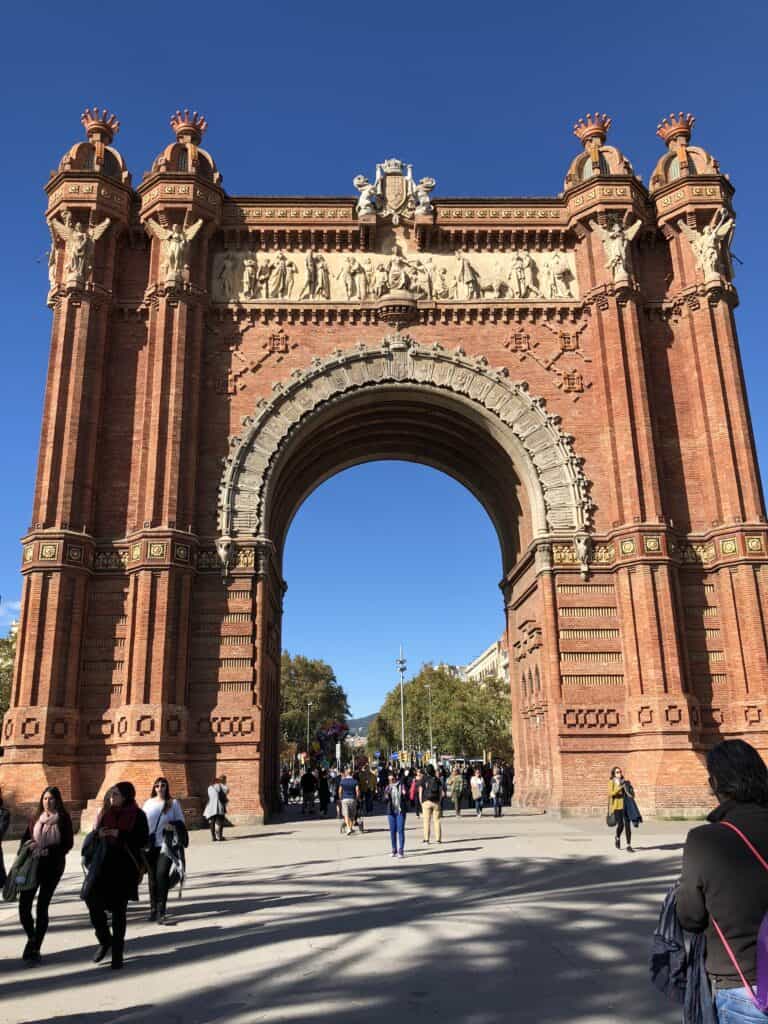 Arc de Triomf in Barcelona with ornate red brick facade and decorative sculptures under a clear blue sky — things to do in Barcelona Spain