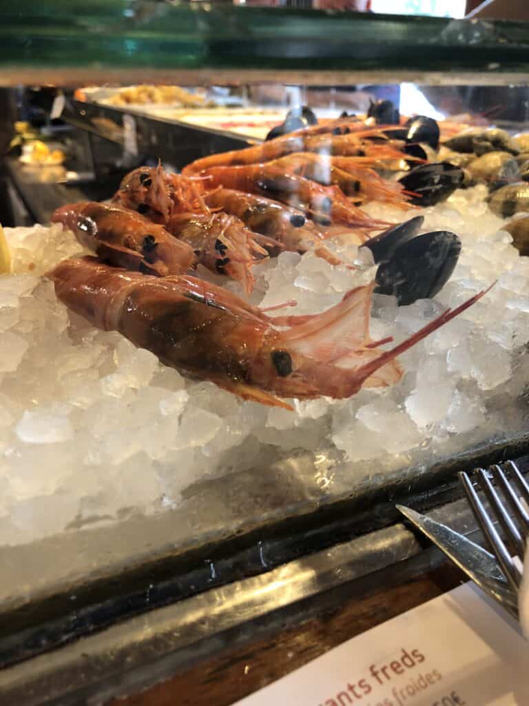 Fresh prawns and mussels on ice at a seafood counter in Barcelona's La Boqueria market — best food markets in Barcelona Spain