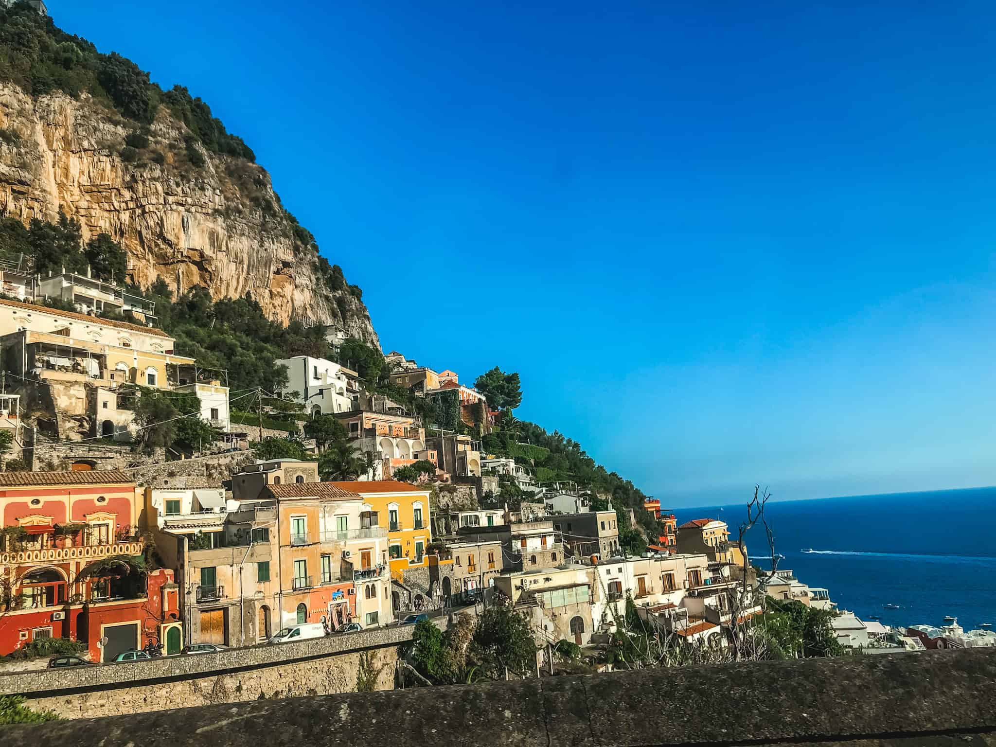 Panoramic sunset view over the Amalfi Coast from Praiano with the church dome, mountain cliffs and calm bay — best views on the Amalfi Coast Italy