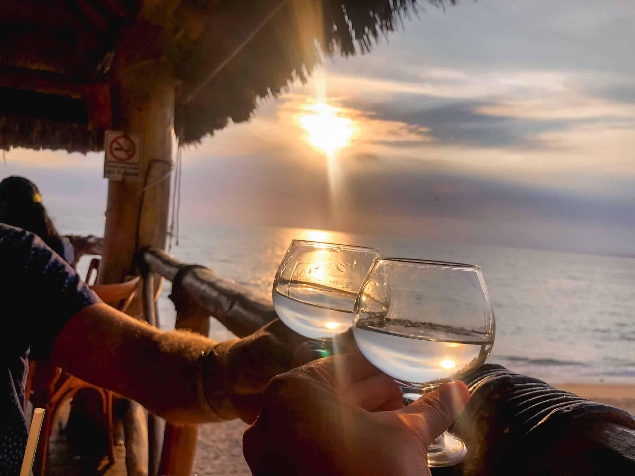 Couple clinking mezcal glasses at a beachfront palapa bar during sunset in Puerto Vallarta, Mexico travel experience