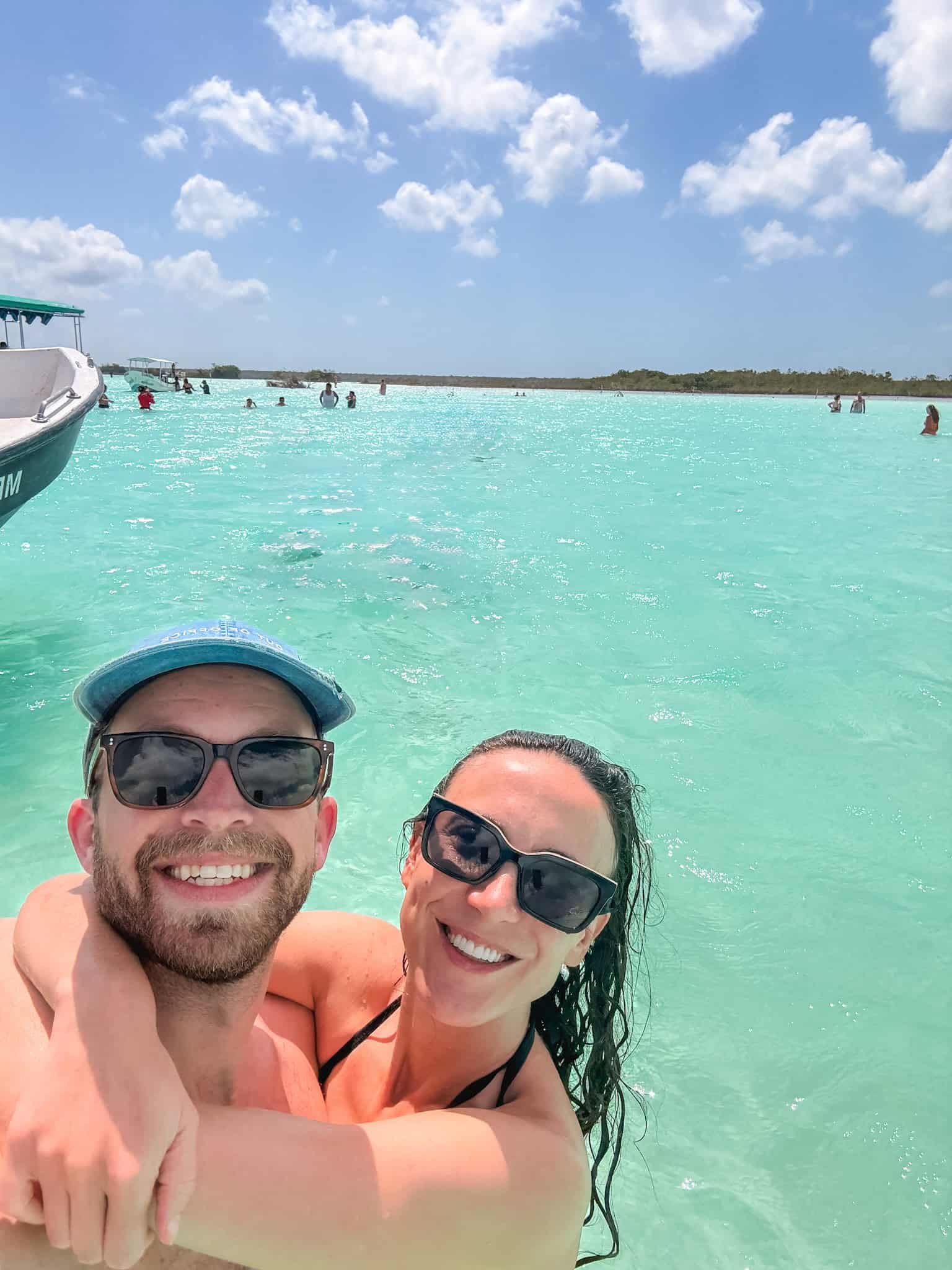 Couple taking a selfie in the crystal-clear turquoise lagoon of Bacalar — is mexico safe to visit for a beach vacation in the Yucatan