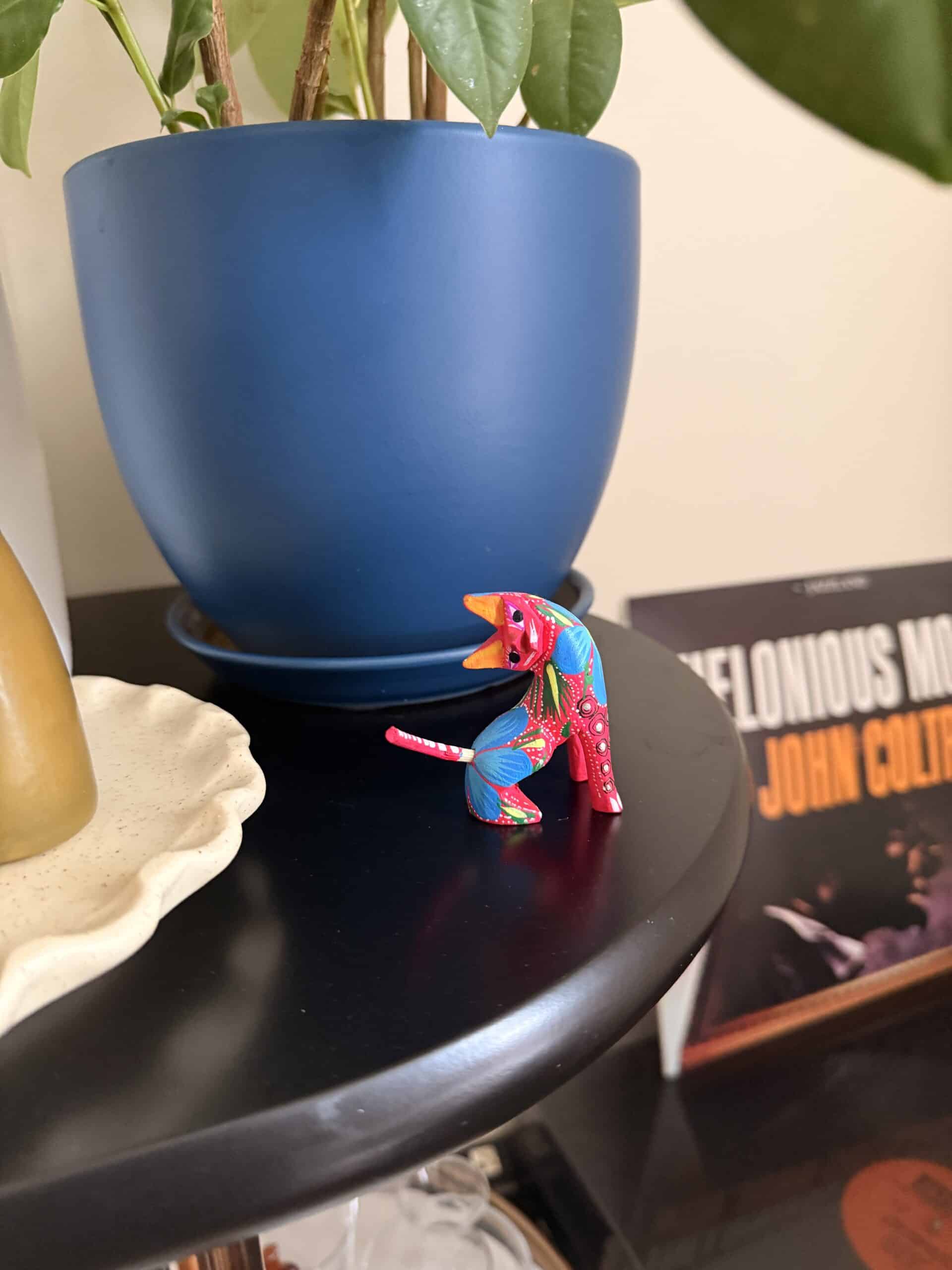 pink cat Alebrije in front of blue pot