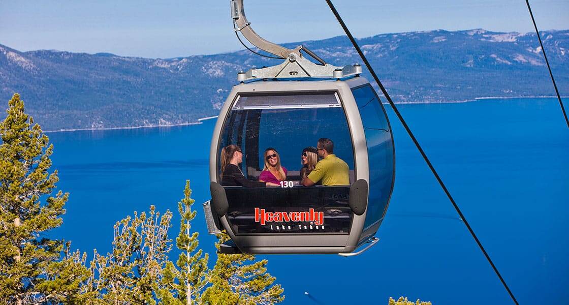 Group of friends riding the Heavenly gondola above Lake Tahoe with sweeping blue water views stretching across the basin below
