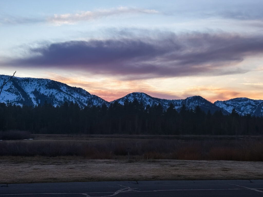 Pink and orange sunset over snow-capped Sierra Nevada peaks above a wetland meadow near South Lake Tahoe in winter