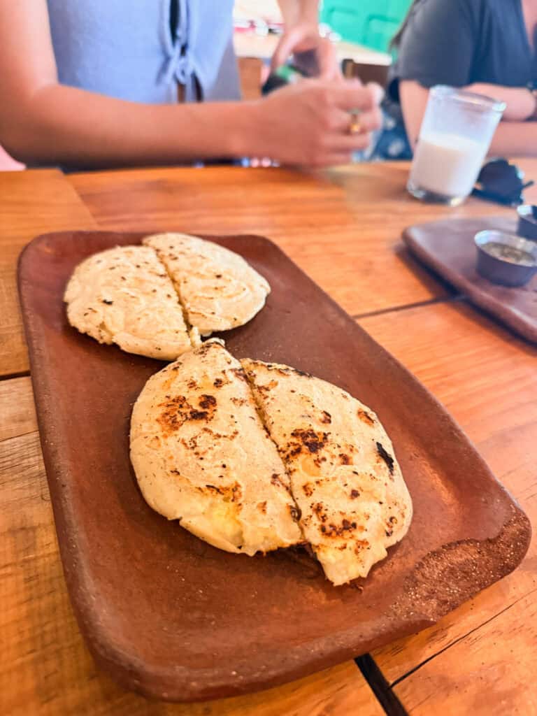 Grilled cheese-stuffed gorditas on a wooden board during a Mexico City food tour, with melted cheese visible through the charred masa dough