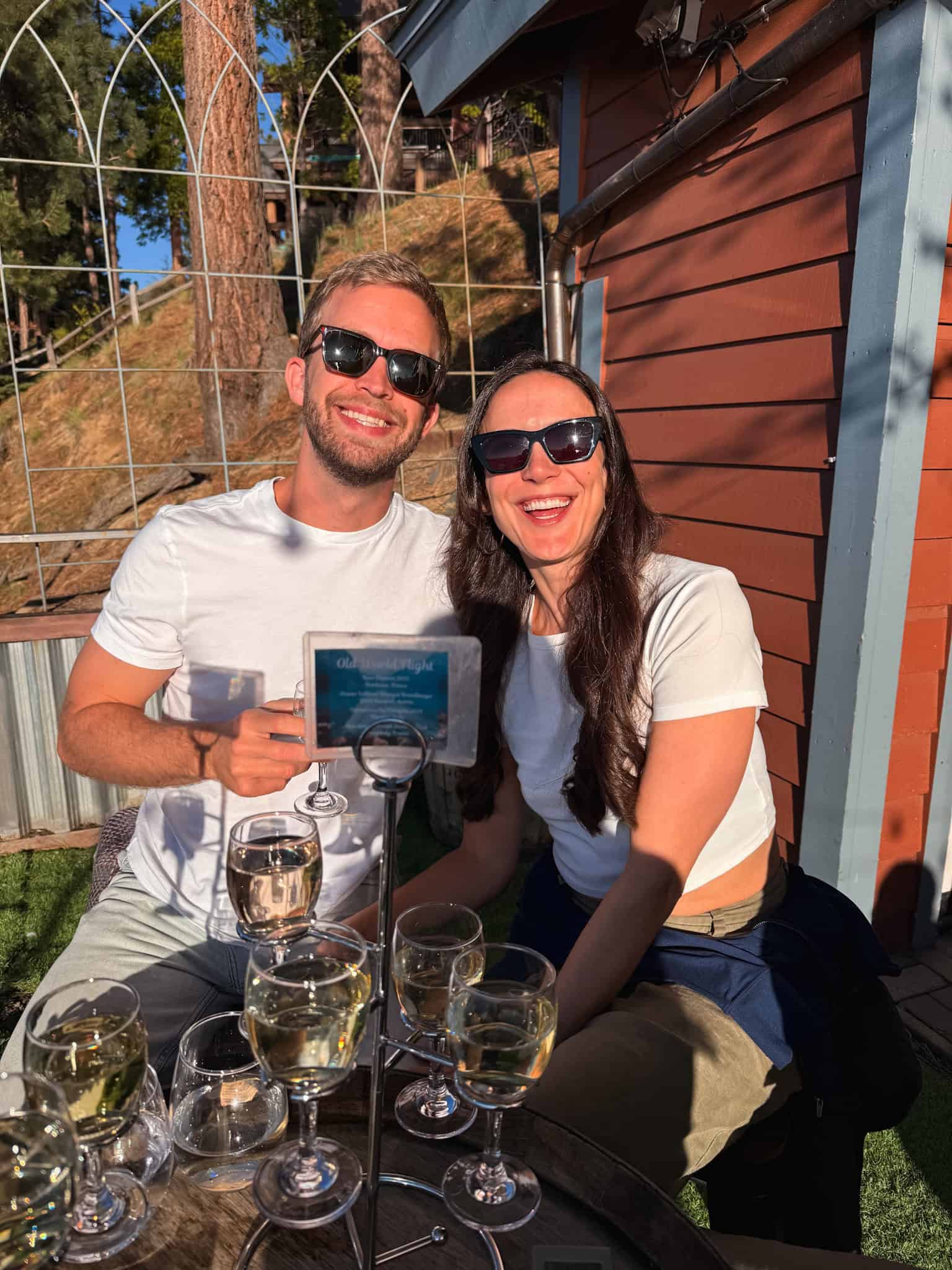 Couple smiling with a white wine flight outdoors at the Idle Hour winery in South Lake Tahoe