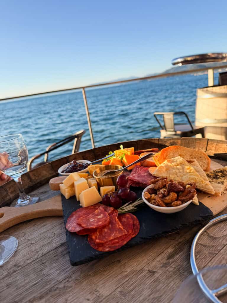 Charcuterie board with salami, cheese, grapes, and crackers on a wine barrel with Lake Tahoe views at the Idle Hour