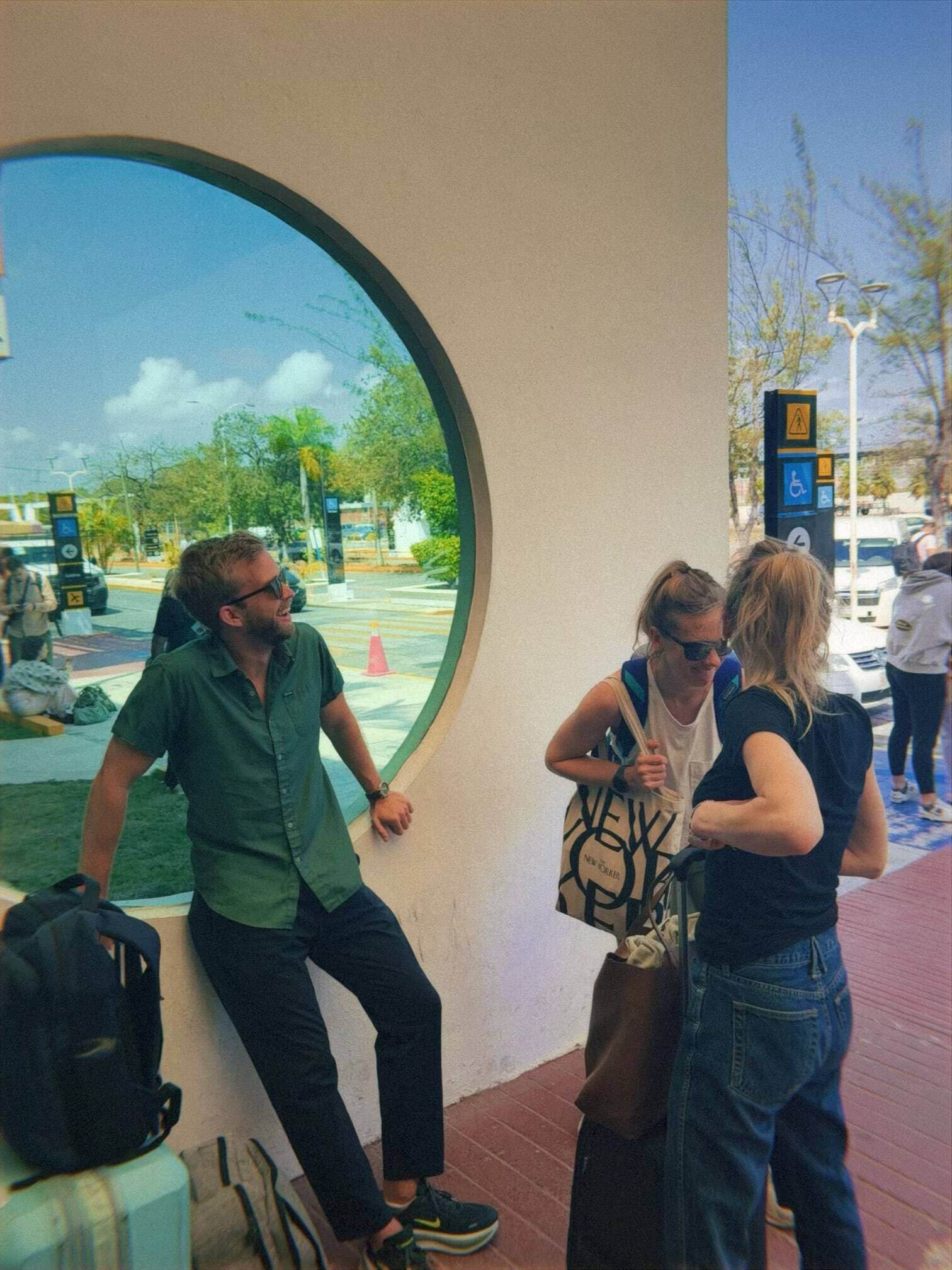 3 people standing in airport with suitcases