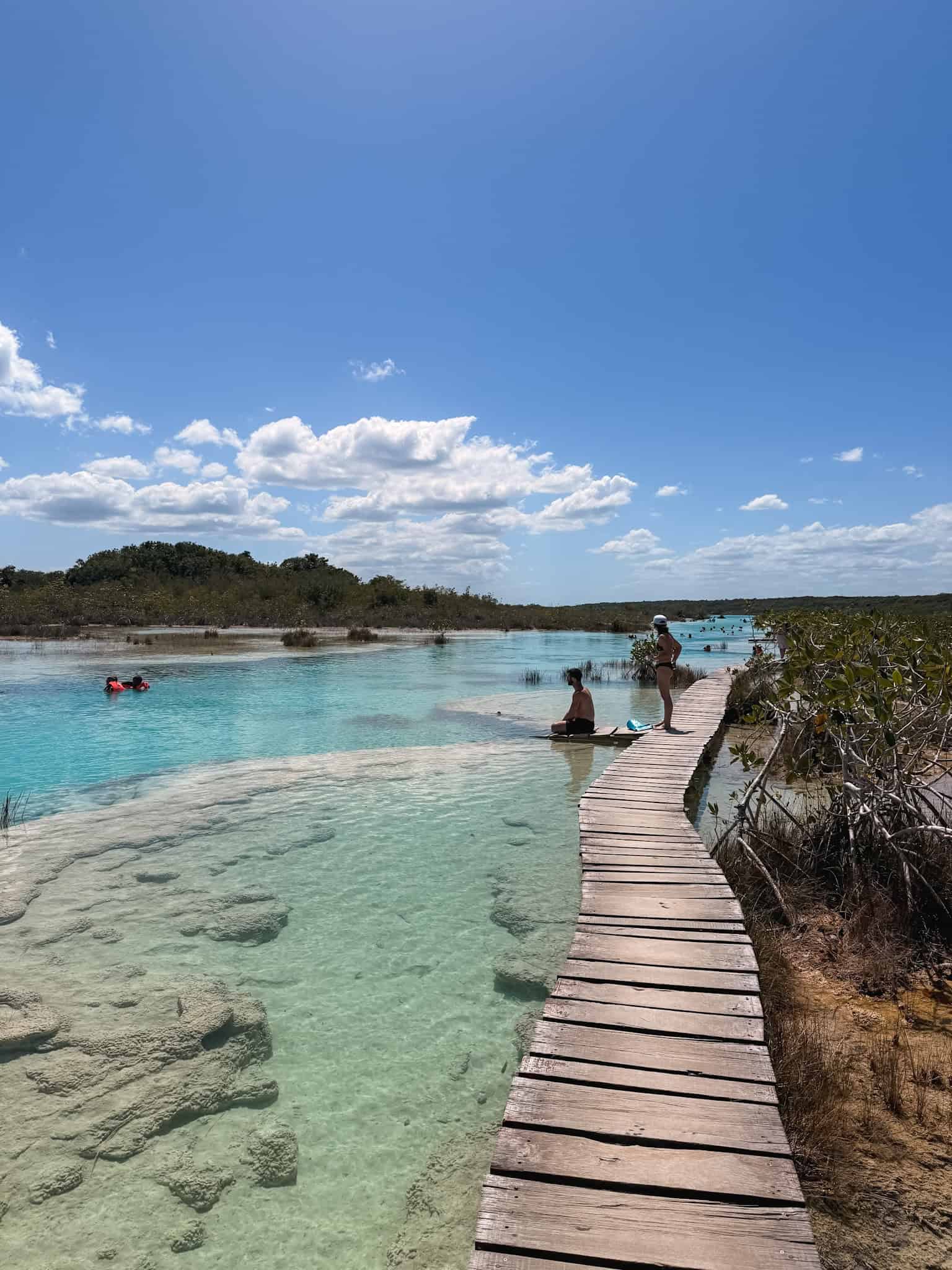 Wooden boardwalk leading through the shallow turquoise waters and white sand flats of Los Rapidos, one of the top activities in Bacalar