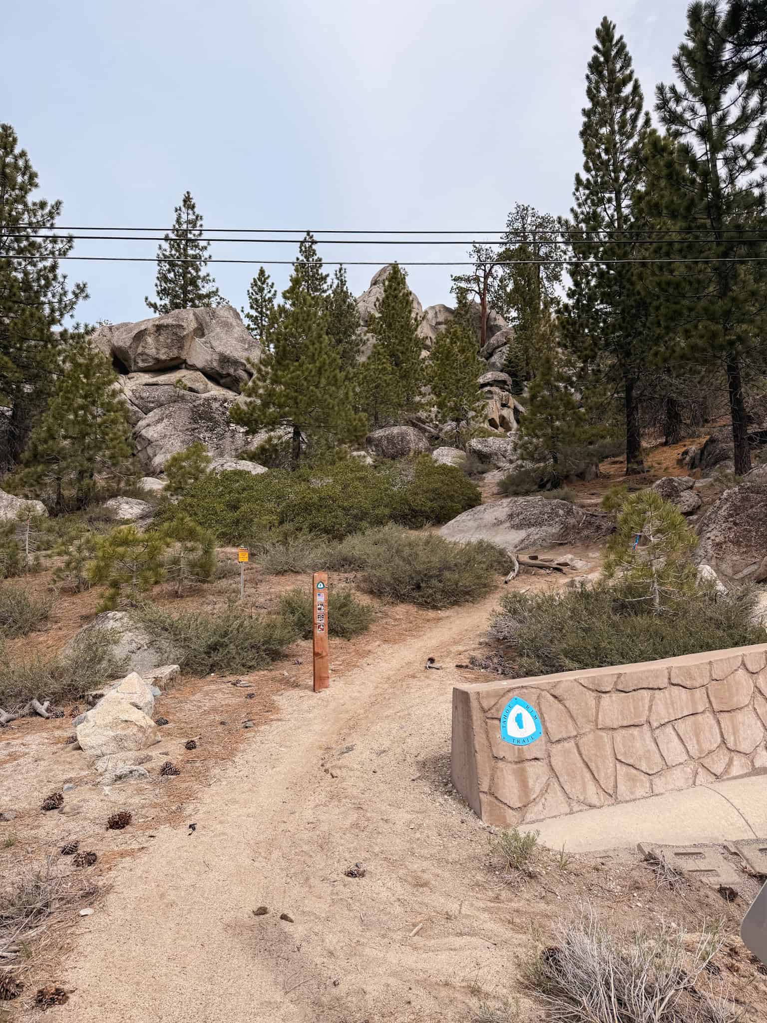 Trailhead entrance to Castle Rock via the Tahoe Rim Trail, with a sandy dirt path leading through granite boulders and pine trees