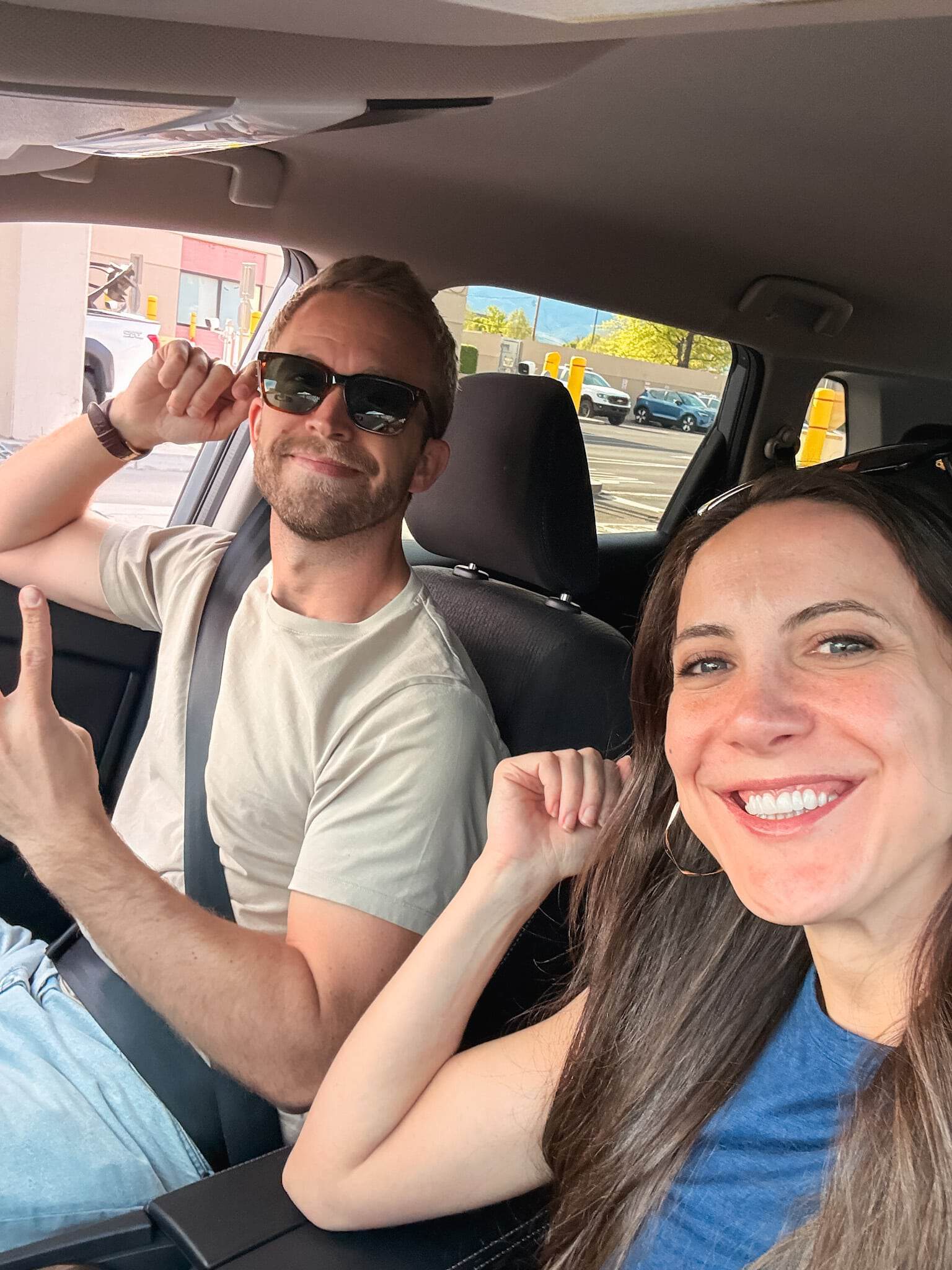 Two people laughing in the front seat of a rental car, driving to Lake Tahoe from Reno airport