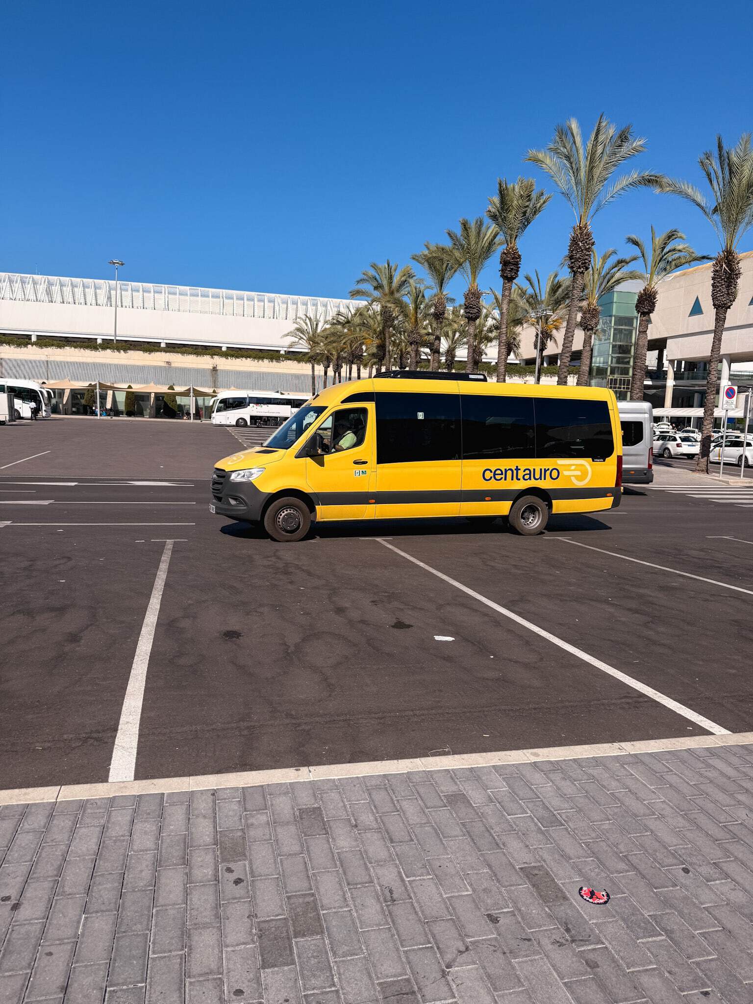 Yellow Centauro shuttle van driving through the car rental pickup area near Palma airport, a key step when renting a car in Mallorca.