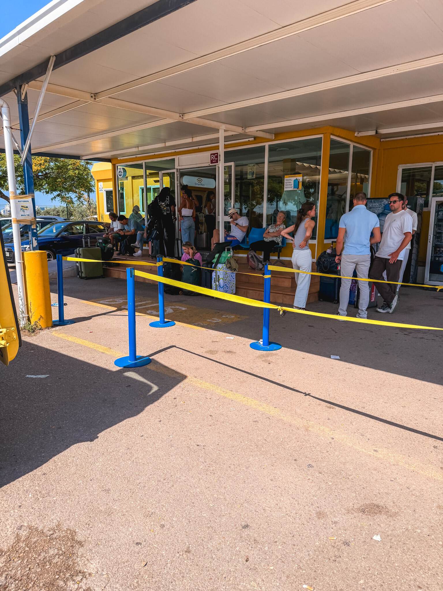 Travelers waiting in line with luggage outside a rental car return office near the airport in Mallorca.
