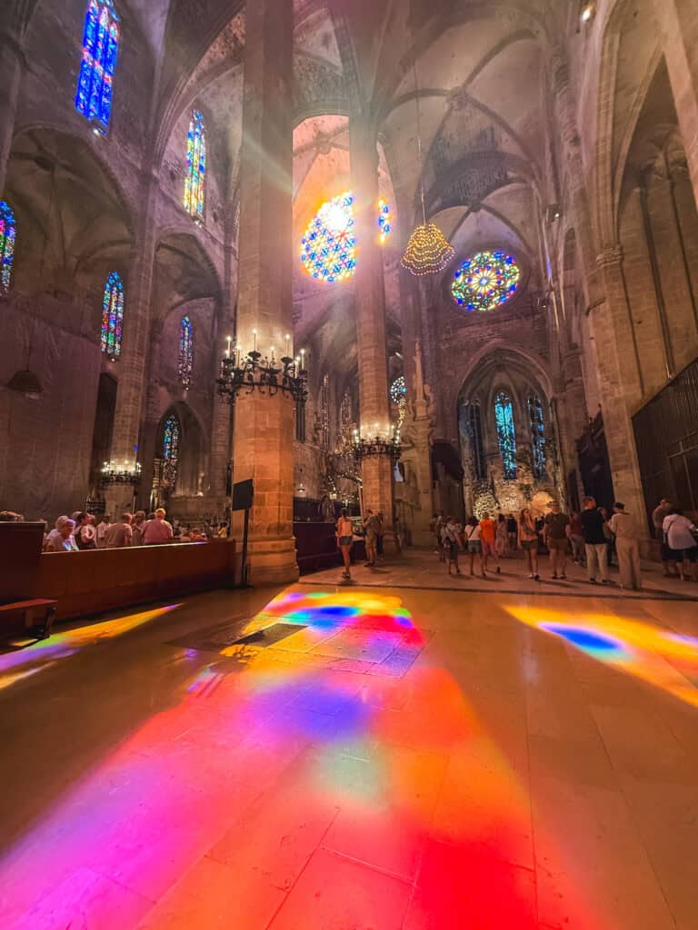 Rainbow light streaming through stained glass inside Palma Cathedral