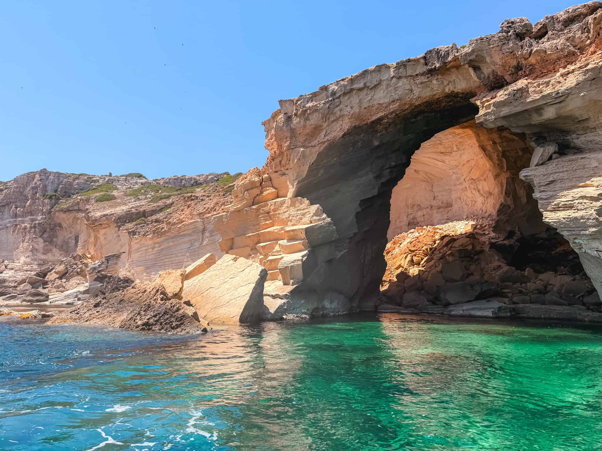 Natural rock arch carved into the limestone cliffs, one of several formations passed along the coast.