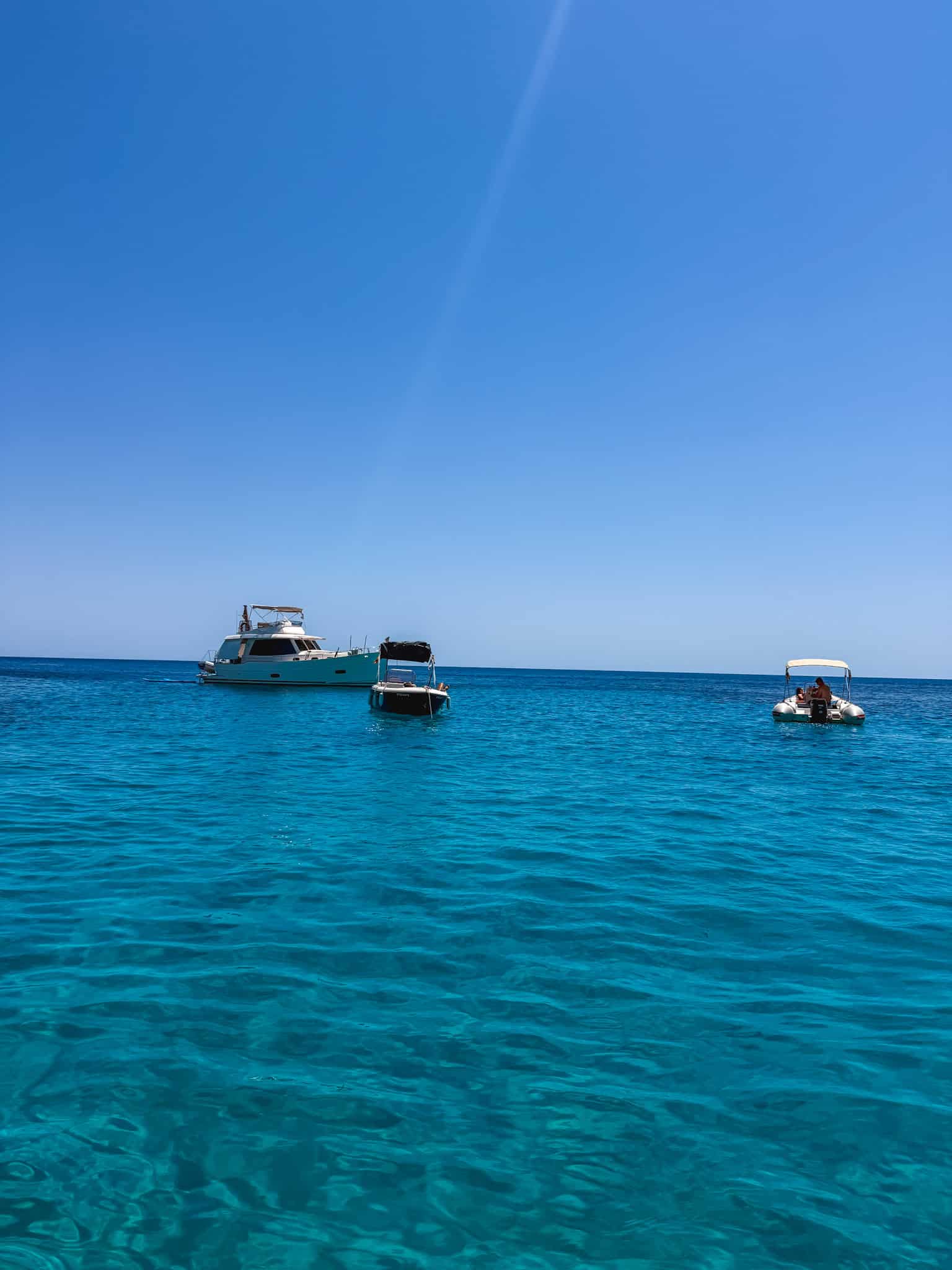 A yacht and smaller boats anchored in open water off the Mallorca coast.