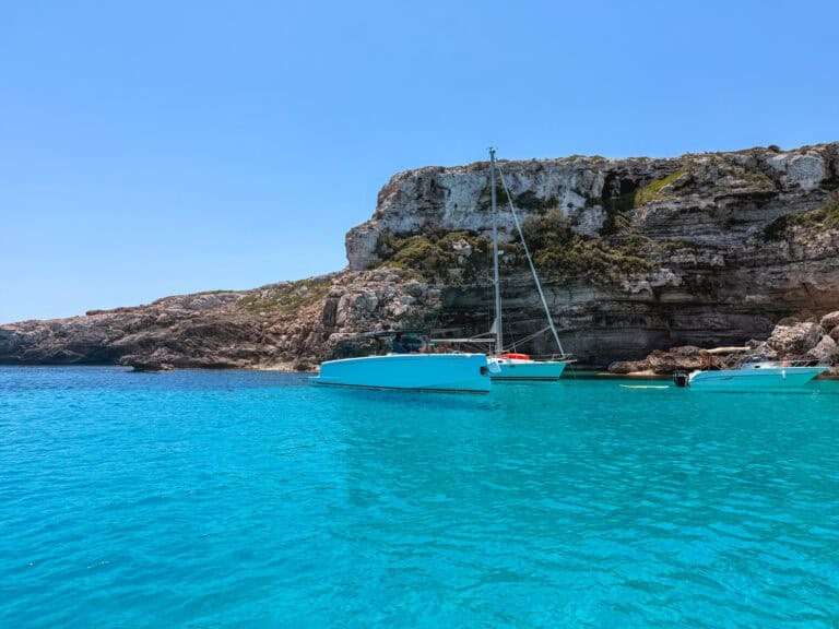 Sailboats and motorboats anchored near the cliffs, a popular anchorage spot for boat tours in Mallorca.