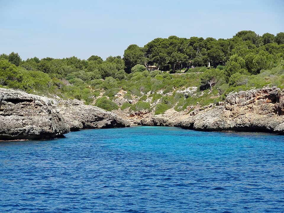 Cala Murta's dark blue bay in Manacor, rocky coastline meeting clear open water