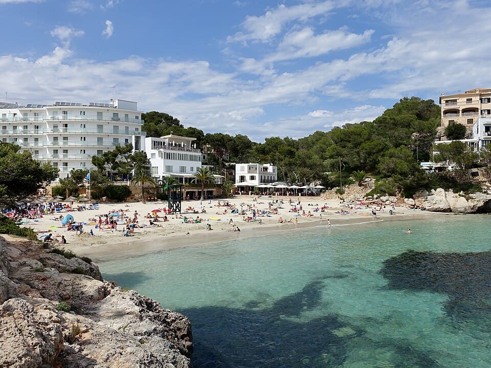Santanyí beach in Cala Santanyí, sunbathers on the sand and a lifeguard tower overlooking the calm bay