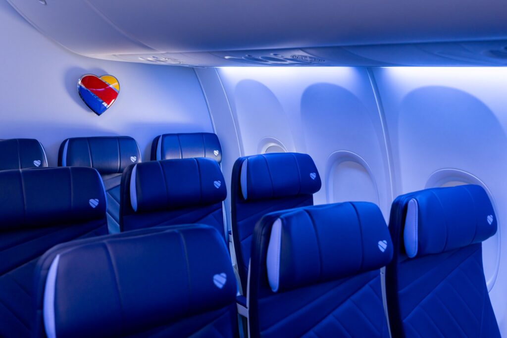 Southwest heart logo on the cabin wall above blue seats with heart embossed headrests on a fly free companion flight