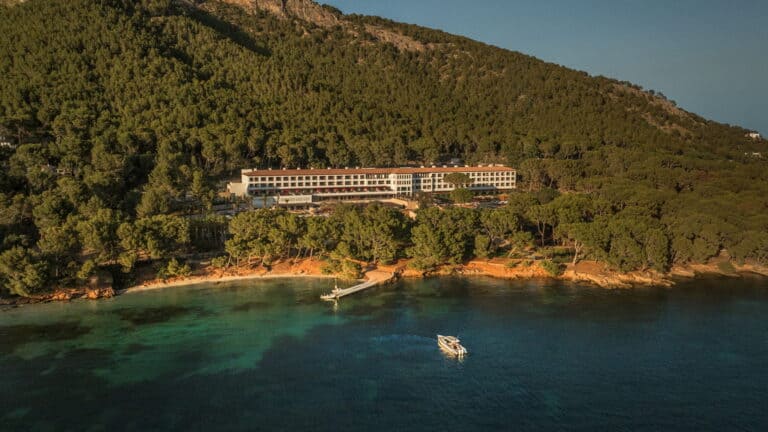 Aerial view of Hotel Formentor nestled in pine forest above a quiet cove, a historic option for where to stay in Mallorca