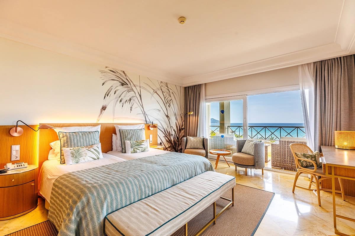 Ocean view suite with a palm leaf mural headboard at Grupotel, a family friendly pick for where to stay in Mallorca